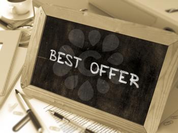 Best Offer Handwritten by White Chalk on a Blackboard. Composition with Small Chalkboard on Background of Working Table with Office Folders, Stationery, Reports. Blurred Background. Toned Image.