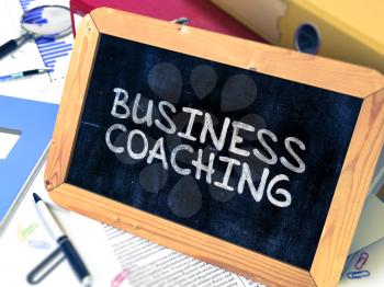 Handwritten Business Coaching on a Chalkboard. Composition with Chalkboard and Ring Binders, Office Supplies, Reports on Blurred Background. Toned Image. 3d Render.