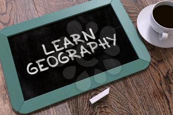 Learn Geography Handwritten on Blue Chalkboard. Business Concept. Composition with Chalkboard and Cup of Coffee. Top View Image. 3d Render.