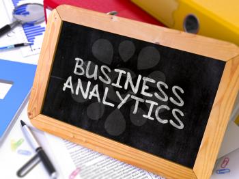 Business Analytics Handwritten by White Chalk on a Blackboard. Composition with Small Chalkboard on Background of Working Table with Office Folders, Stationery, Reports. Blurred, Toned 3d Image.