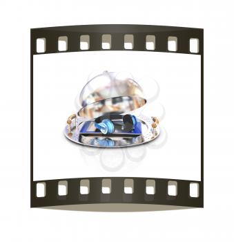 Phone and headphones on glossy salver dish under a cover on a white background. The film strip