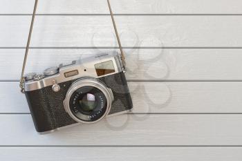 Vintage retro photo camera hanging on the white wooden wall. 3d illustration