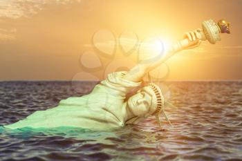 Destroyed Statue of liberty in the sunset half covered by rising ocean level.  Apocalypse of USA, America and the end of civilization concept. 3d illustration