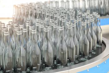 Empty  glass bottles on conveyor belt in factory or glass manufacture. 3d illustration