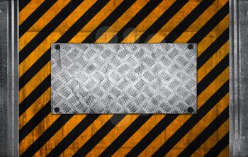 Metal panel on black and yellow striped caution pattern of industrial concrete wall