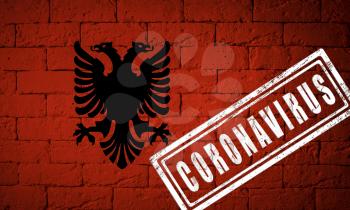 Flag of the Albania with original proportions. stamped of Coronavirus. brick wall texture. Corona virus concept. On the verge of a COVID-19 or 2019-nCoV Pandemic.