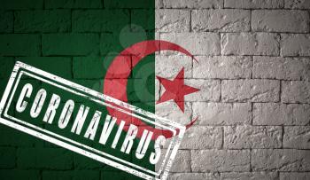 Flag of the Algeria with original proportions stamped of Coronavirus. brick wall texture. Corona virus concept. On the verge of a COVID-19 or 2019-nCoV Pandemic.