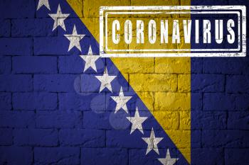 Flag of the Bosnia and Herzegovina with original proportions. stamped of Coronavirus. brick wall texture. Corona virus concept. On the verge of a COVID-19 or 2019-nCoV Pandemic.