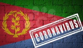 Flag of the Eritrea on brick wall texture. stamped of Coronavirus. Corona virus concept. On the verge of a COVID-19 or 2019-nCoV Pandemic. Novel Chinese Coronavirus outbreak