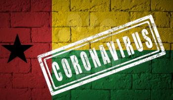 Flag of the Guinea-Bissau on brick wall texture. stamped of Coronavirus. Corona virus concept. On the verge of a COVID-19 or 2019-nCoV Pandemic. Novel Chinese Coronavirus outbreak