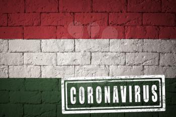 Flag of the Hungary with original proportions. stamped of Coronavirus. brick wall texture. Corona virus concept. On the verge of a COVID-19 or 2019-nCoV Pandemic.