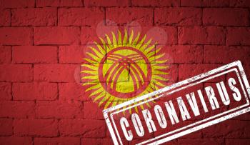 Flag of the Kyrgyzstan with original proportions. stamped of Coronavirus. brick wall texture. Corona virus concept. On the verge of a COVID-19 or 2019-nCoV Pandemic.