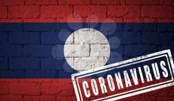 Flag of the Laos with original proportions. stamped of Coronavirus. brick wall texture. Corona virus concept. On the verge of a COVID-19 or 2019-nCoV Pandemic.