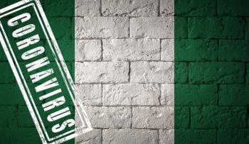 Flag of the Nigeria with original proportions. stamped of Coronavirus. brick wall texture. Corona virus concept. On the verge of a COVID-19 or 2019-nCoV Pandemic.