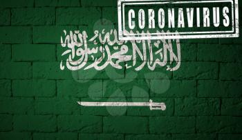 Flag of the Saudi Arabia with original proportions. stamped of Coronavirus. brick wall texture. Corona virus concept. On the verge of a COVID-19 or 2019-nCoV Pandemic.