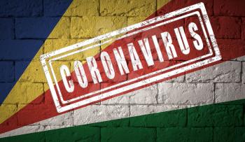 Flag of the Seychelles on brick wall texture. stamped of Coronavirus. Corona virus concept. On the verge of a COVID-19 or 2019-nCoV Pandemic. Novel Chinese Coronavirus outbreak