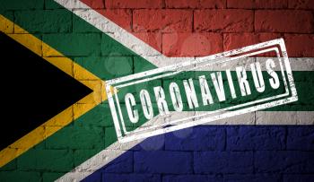 Flag of the South Africa with original proportions. stamped of Coronavirus. brick wall texture. Corona virus concept. On the verge of a COVID-19 or 2019-nCoV Pandemic.