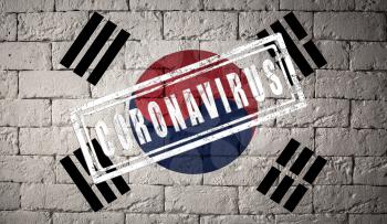 Flag of the South Korea with original proportions stamped of Coronavirus. brick wall texture. Corona virus concept. On the verge of a COVID-19 or 2019-nCoV Pandemic.