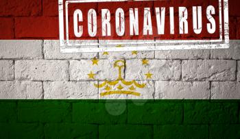 Flag of the Tajikistan with original proportions. stamped of Coronavirus. brick wall texture. Corona virus concept. On the verge of a COVID-19 or 2019-nCoV Pandemic.