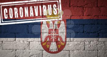 Flag of the Republic of Serbia with original proportions. stamped of Coronavirus. brick wall texture. Corona virus concept. On the verge of a COVID-19 or 2019-nCoV Pandemic.