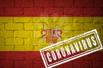 Flag of the Spain with original proportions. stamped of Coronavirus. brick wall texture. Corona virus concept. On the verge of a COVID-19 or 2019-nCoV Pandemic.