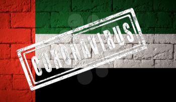 Flag of the UAE or United Arab Emirates with original proportions. stamped of Coronavirus. brick wall texture. Corona virus concept. On the verge of a COVID-19 or 2019-nCoV Pandemic.