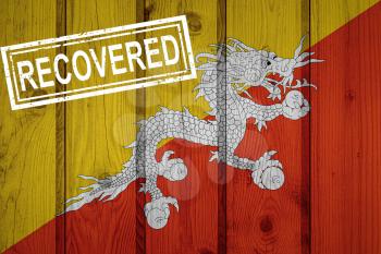 flag of Bhutan that survived or recovered from the infections of corona virus epidemic or coronavirus. Grunge flag with stamp Recovered