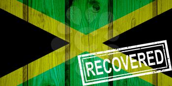flag of Jamaica that survived or recovered from the infections of corona virus epidemic or coronavirus. Grunge flag with stamp Recovered