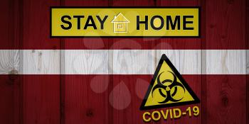 Flag of the Latvia in original proportions. Quarantine and isolation - Stay at home. flag with biohazard symbol and inscription COVID-19.