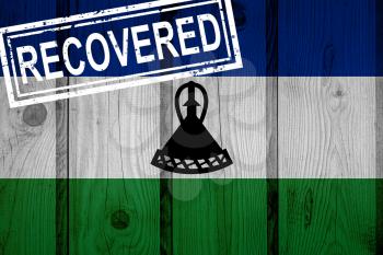 flag of Lesotho that survived or recovered from the infections of corona virus epidemic or coronavirus. Grunge flag with stamp Recovered