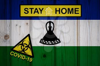 Flag of the Lesotho in original proportions. Quarantine and isolation - Stay at home. flag with biohazard symbol and inscription COVID-19.