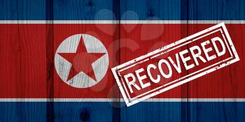 flag of North Korea that survived or recovered from the infections of corona virus epidemic or coronavirus. Grunge flag with stamp Recovered