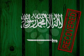 flag of Saudi Arabia that survived or recovered from the infections of corona virus epidemic or coronavirus. Grunge flag with stamp Recovered