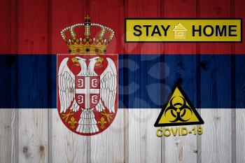 Flag of the Serbia in original proportions. Quarantine and isolation - Stay at home. flag with biohazard symbol and inscription COVID-19.