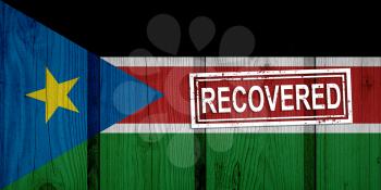 flag of South Sudan that survived or recovered from the infections of corona virus epidemic or coronavirus. Grunge flag with stamp Recovered