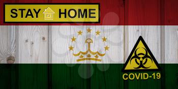 Flag of the Tajikistan in original proportions. Quarantine and isolation - Stay at home. flag with biohazard symbol and inscription COVID-19.