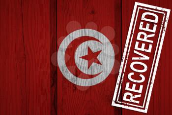 flag of Tunisia that survived or recovered from the infections of corona virus epidemic or coronavirus. Grunge flag with stamp Recovered