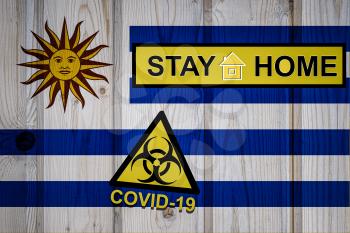 Flag of the Uruguay in original proportions. Quarantine and isolation - Stay at home. flag with biohazard symbol and inscription COVID-19.